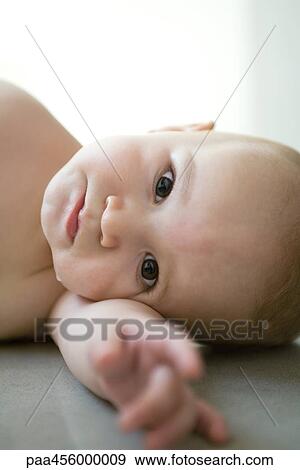 Baby looking at camera, head resting on arm, on side View Large Photo Image Stock Photo - Baby looking at camera, head resting on arm, on side. Fotosearch