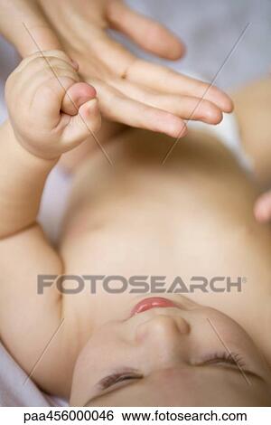 Baby lying on back, holding adult's finger View Large Photo Image Stock Photograph - Baby lying on back, holding adult's finger. Fotosearch