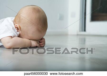 Baby lying on stomach, head resting on arms, obscured face View Large Photo Image Stock Image - Baby lying on stomach, head resting on arms, obscured face. Fotosearch