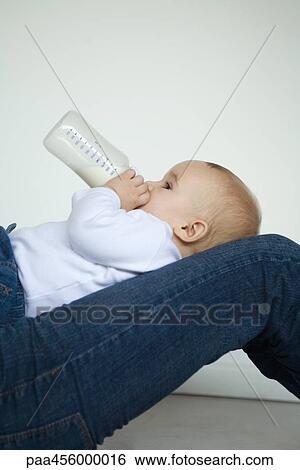 Baby reclining on lap, drinking milk from bottle, side view View Large Photo Image Stock Photograph - Baby reclining on lap, drinking milk from bottle, side view. Fotosearch