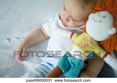Baby sleeping, holding doll View Large Photo Image Stock Image - Baby sleeping, holding doll. Fotosearch