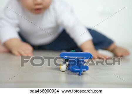 Toy airplane on floor, baby in background View Large Photo Image Picture - Toy airplane on floor, baby in background. Fotosearch
