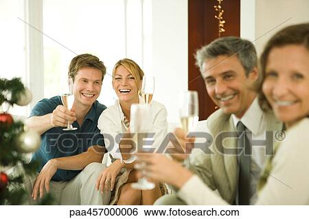 Stock Photograph - Adult friends making a toast with champagne, smiling at camera. Fotosearch