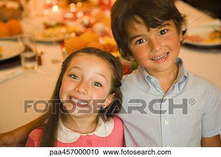 Stock Image - Boy and girl smiling at camera, portrait. Fotosearch