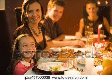 Family eating festive dinner, looking toward camera, smiling View Large Photo Image Stock Photo - Family eating festive dinner, looking toward camera, smiling. Fotosearch