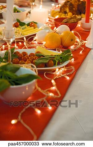 Stock Image - Festive dinner table, meal, decorated with Christmas lights. Fotosearch