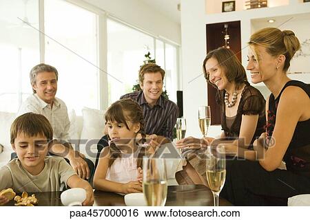 Stock Photograph - Four adults drinking champagne, watching children, smiling. Fotosearch