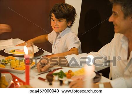 Man and boy sitting at dinner table, smiling View Large Photo Image Stock Image - Man and boy sitting at dinner table, smiling. Fotosearch