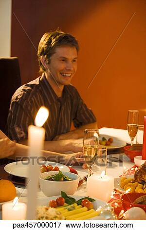 Stock Photo - Man sitting at dinner table, smiling. Fotosearch