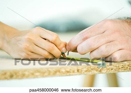 Stock Photograph - Couple measuring wood, cropped view of hands. Fotosearch
