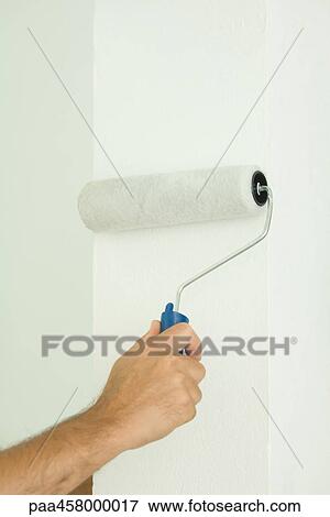 Stock Photo - Man painting wall with paint roller, cropped view of hand. Fotosearch