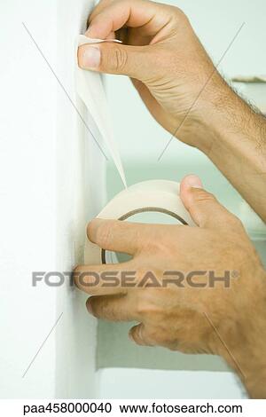 Stock Image - Man taping with adhesive tape, cropped view of hands. Fotosearch