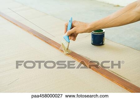 Stock Photo - Woman painting wood plank with paintbrush, cropped view of hand. Fotosearch