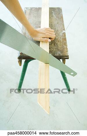 Picture - Woman sawing wood with saw, cropped view of hand. Fotosearch