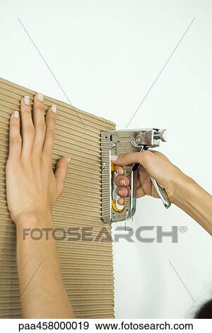 Stock Photo - Woman stapling corrugated cardboard, cropped view of hands. Fotosearch