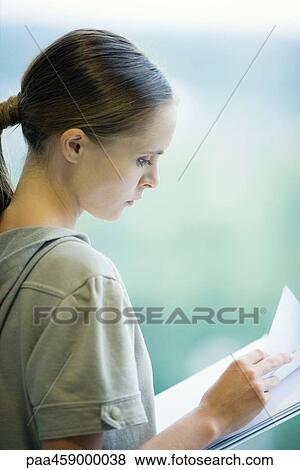 Female student looking down at paper, side view View Large Photo Image Stock Photo - Female student looking down at paper, side view. Fotosearch