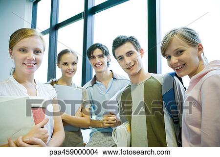 Picture - Five students standing in front of window, smiling at camera, group portrait. Fotosearch