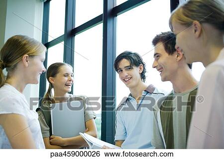 Stock Photograph - Group of students standing in front of window, smiling, one looking at camera. Fotosearch
