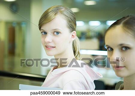 Two female students smiling at camera, side view View Large Photo Image Stock Photo - Two female students smiling at camera, side view. Fotosearch