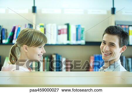 Two students in campus library next to book shelf, smiling, head and shoulders View Large Photo Image Stock Photo - Two students in campus library next to book shelf, smiling, head and shoulders. Fotosearch