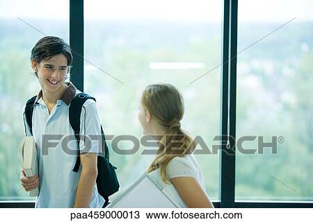 Two students in front of window, looking at each other, smiling View Large Photo Image Stock Image - Two students in front of window, looking at each other, smiling. Fotosearch