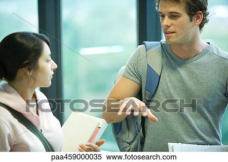 Two students standing together, chatting View Large Photo Image Stock Photography - Two students standing together, chatting. Fotosearch