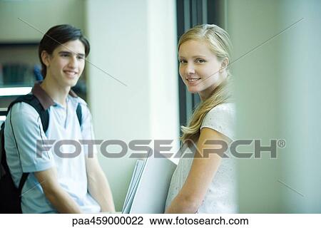 Two students standing together, one looking over her shoulder at camera View Large Photo Image Stock Image - Two students standing together, one looking over her shoulder at camera. Fotosearch