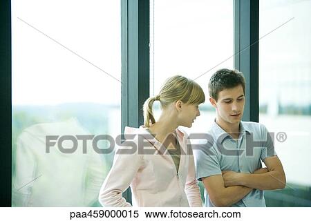 Stock Photography - Two young friends side by side in front of window, talking. Fotosearch