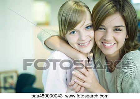 Two young friends smiling at camera, cheek to cheek, one's arm around the other's shoulder View Large Photo Image Stock Image - Two young friends smiling at camera, cheek to cheek, one's arm around the other's shoulder. Fotosearch
