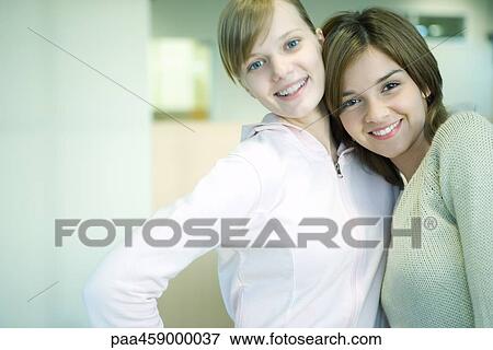 Two young friends standing together, smiling, one leaning her head on the other's shoulder View Large Photo Image Stock Photo - Two young friends standing together, smiling, one leaning her head on the other's shoulder. Fotosearch