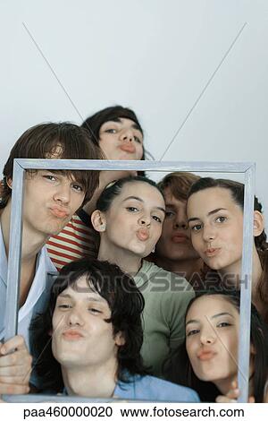 Group of young friends posing for photo, holding up picture frame, puckering at camera, portrait View Large Photo Image Stock Image - Group of young friends posing for photo, holding up picture frame, puckering at camera, portrait. Fotosearch