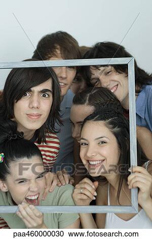 Group of young friends posing for photo, holding up picture frame, smiling at camera, portrait View Large Photo Image Stock Image - Group of young friends posing for photo, holding up picture frame, smiling at camera, portrait. Fotosearch