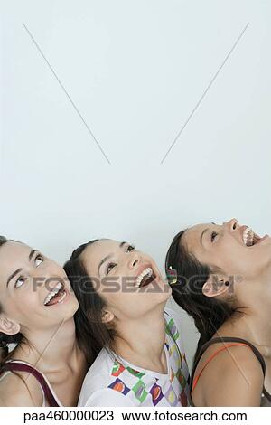 Three young female friends tilting heads back, laughing, head and shoulders, portrait View Large Photo Image Stock Image - Three young female friends tilting heads back, laughing, head and shoulders, portrait. Fotosearch