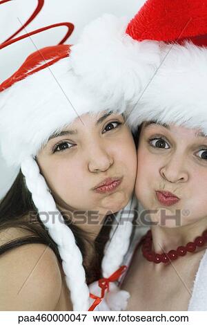 Two young female friends dressed in Christmas costumes, puffing out cheeks, looking at camera, portrait View Large Photo Image Stock Photo - Two young female friends dressed in Christmas costumes, puffing out cheeks, looking at camera, portrait. Fotosearch