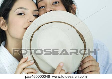 Two young female friends dressed in button down shirts, looking over hat at camera, portrait View Large Photo Image Stock Photo - Two young female friends dressed in button down shirts, looking over hat at camera, portrait. Fotosearch