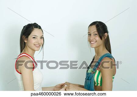 Two young female friends holding hands, side view, smiling at camera, portrait View Large Photo Image Stock Photograph - Two young female friends holding hands, side view, smiling at camera, portrait. Fotosearch
