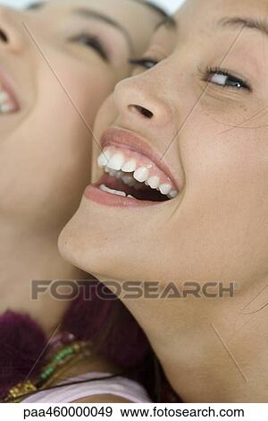 Two young female friends laughing, one looking at camera, extreme close-up of faces, cropped View Large Photo Image Stock Photo - Two young female friends laughing, one looking at camera, extreme close-up of faces, cropped. Fotosearch