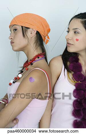 Two young female friends, one turning back to the other, pouting, waist up, portrait View Large Photo Image Picture - Two young female friends, one turning back to the other, pouting, waist up, portrait. Fotosearch