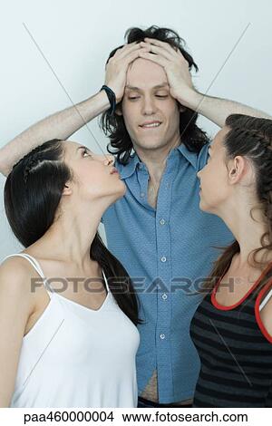 Two young females looking back at teen boy pushing hair back, biting lip View Large Photo Image Picture - Two young females looking back at teen boy pushing hair back, biting lip. Fotosearch