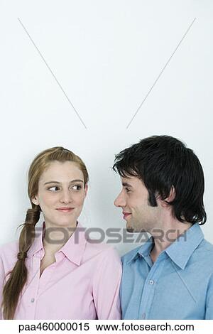 Young couple smirking at each other, head and shoulders, portrait View Large Photo Image Stock Photography - Young couple smirking at each other, head and shoulders, portrait. Fotosearch