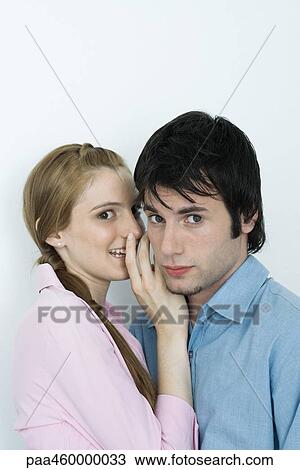 Young couple, woman whispering to man, both looking at camera, portrait View Large Photo Image Stock Image - Young couple, woman whispering to man, both looking at camera, portrait. Fotosearch
