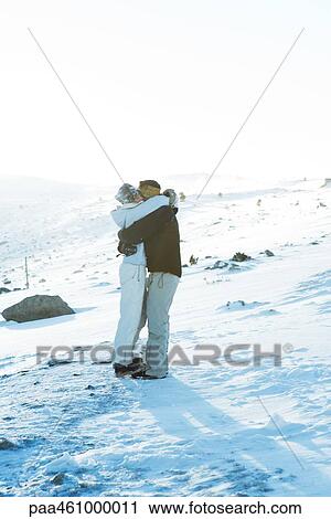 Stock Image - Father and daughter standing on ski slope, hugging. Fotosearch