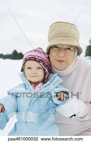 Stock Image - Grandmother and granddaughter smiling, dressed in winter clothing, portrait. Fotosearch