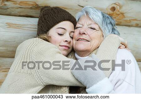 Stock Image - Grandmother and granddaughter embracing, eyes closed, portrait. Fotosearch