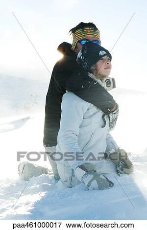 Stock Photo - Mature man embracing teenage girl, both kneeling in snow. Fotosearch