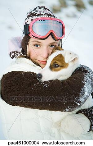 Picture - Teenage girl embracing dog, dressed in winter clothing, smiling at camera, portrait. Fotosearch
