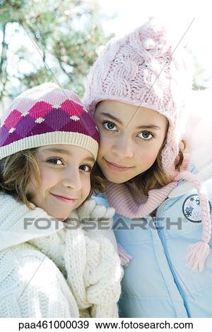 Stock Photo - Two sisters smiling at camera, cheek to cheek, both wearing knit hats, portrait. Fotosearch