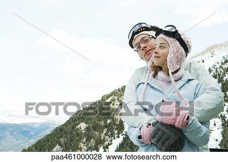 Stock Photo - Two young friends embracing, male smiling over female's shoulder, both smiling. Fotosearch