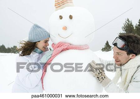 Two young friends peeking around snowman at each other, smiling View Large Photo Image Stock Image - Two young friends peeking around snowman at each other, smiling. Fotosearch