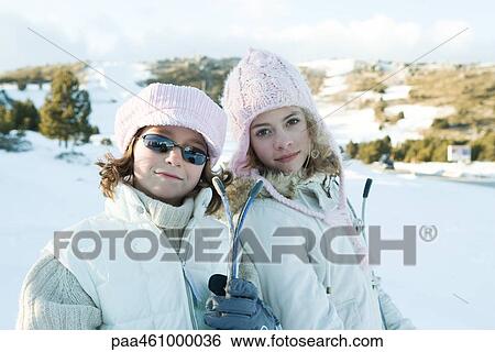 Stock Photograph - Two young skiers smiling at camera, portrait. Fotosearch